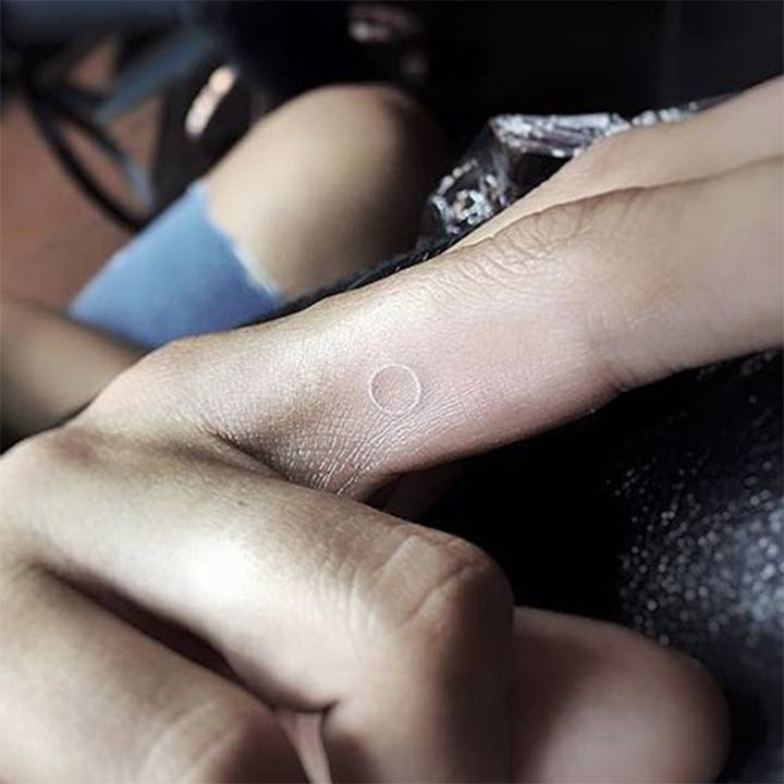 Tiny white circle tattoo