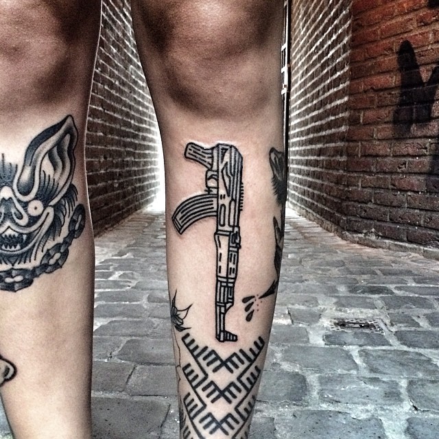 Ak 47 and ornament tattoo on the leg 