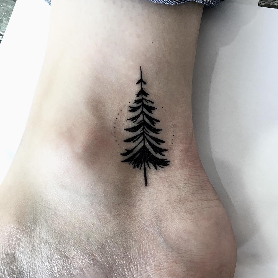 Black pine tree tattoo on the inner ankle