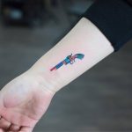 Colorful revolver tattoo on the wrist