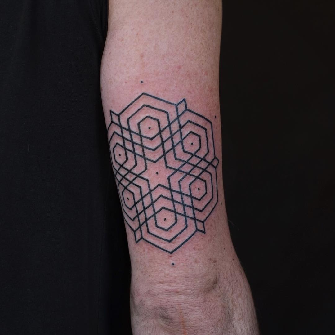 Geometric ornament tattoo above the elbow