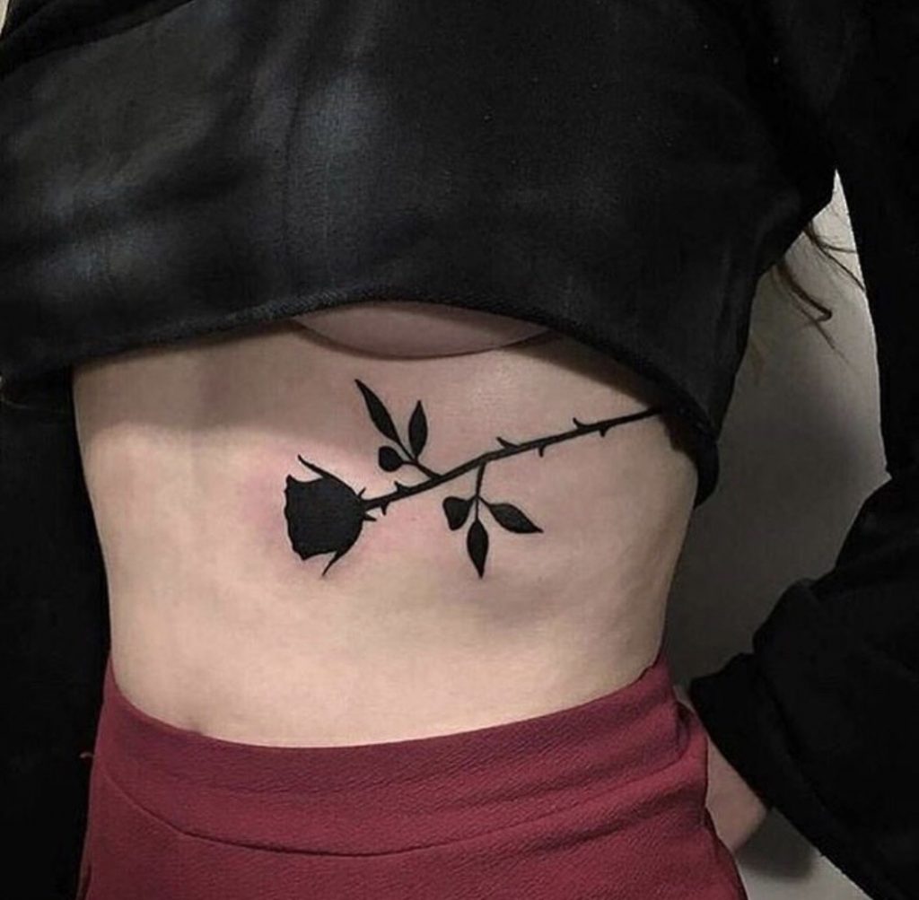Minimalist black rose tattoo on the rib