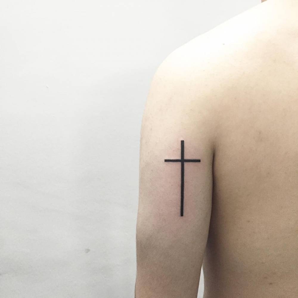 Minimalist cross tattoo on the arm