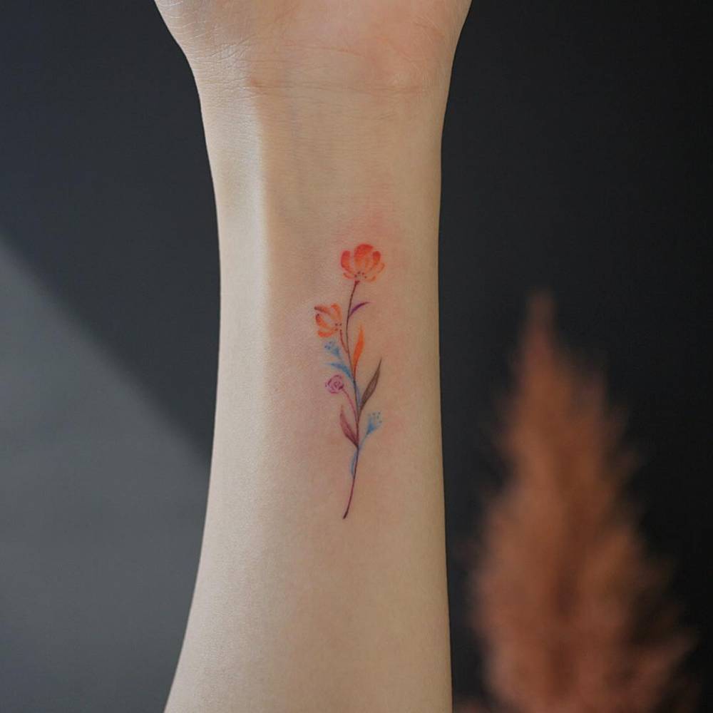 Small watercolor flower tattoo on the inner wrist 