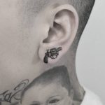 Small revolver tattoo on the ear