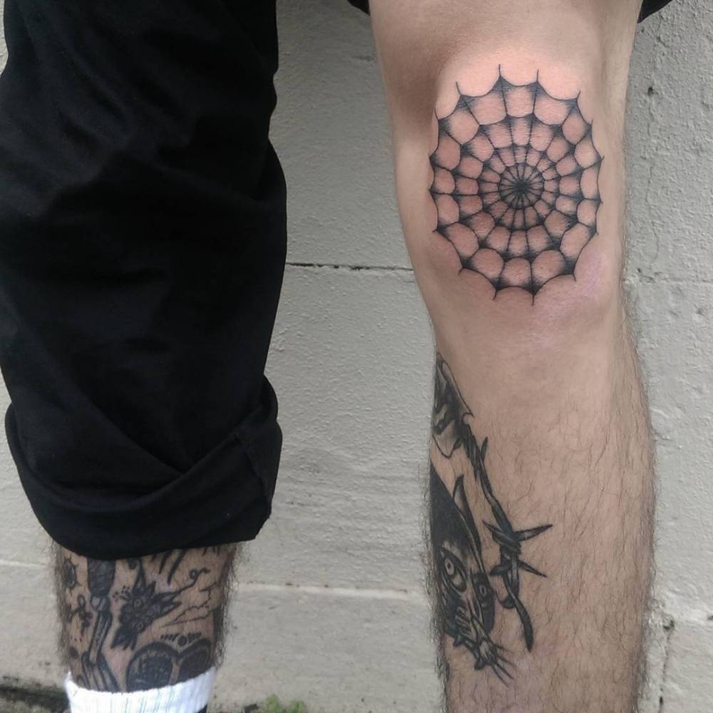 Black spiderweb tattoo on the left knee 