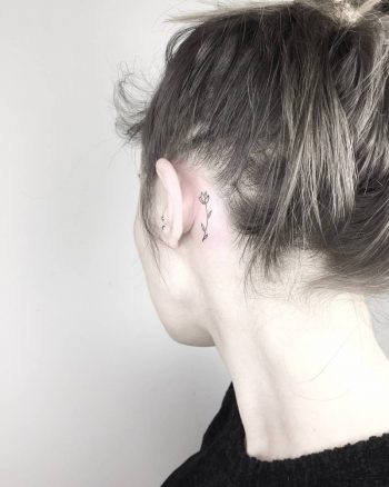 Tiny tulip tattoo behind the left ear
