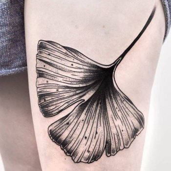 Black ginkgo leaf tattoo on the thigh