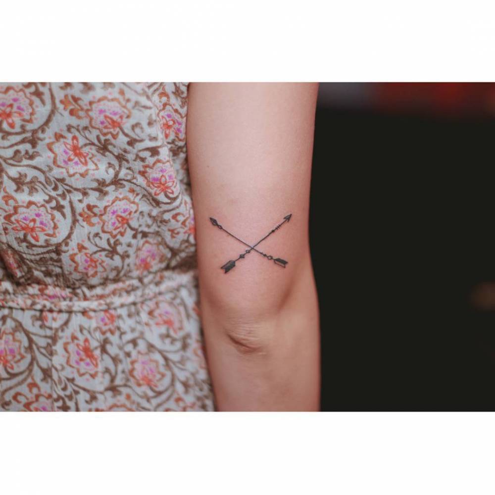 Minimalist crossed arrows tattoo