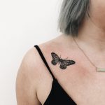 Black small butterfly tattoo on the clavicle bone