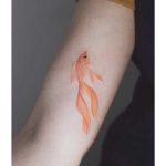 Golden fish tattoo on the forearm
