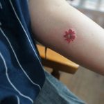 Hand-poked red flower by tattooist baka