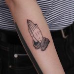 Praying hands tattoo on the forearm