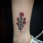 Red and green flower tattoo on ankle
