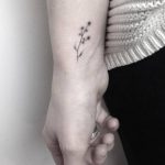 Small hand-poked flower tattoo on the wrist