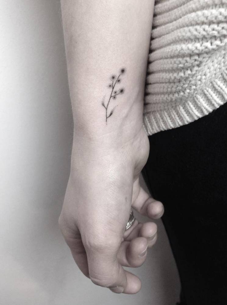 Small hand-poked flower tattoo on the wrist