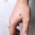 Tiny black dot tattoo on the hand