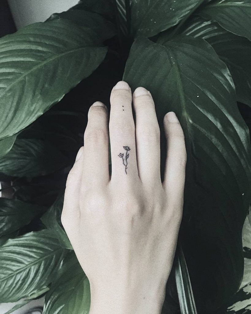 Tiny black floral piece on the finger