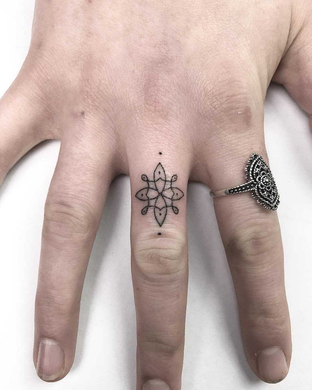 Tiny flower tattoo on the middle finger