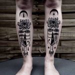 Abstract face and flower tattoos on shins