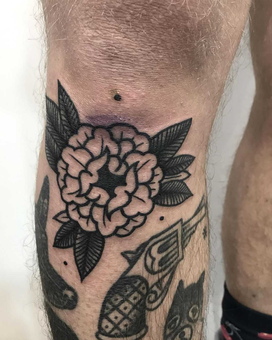 Black flower tattoo below the knee