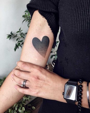 Black gradient heart tattoo on the arm