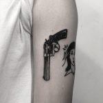 Black revolver tattoo on the arm