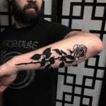 Black rose tattoo on the left forearm