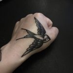 Black swallow tattoo on the left hand