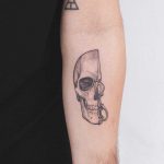 Half skull tattoo on the left forearm