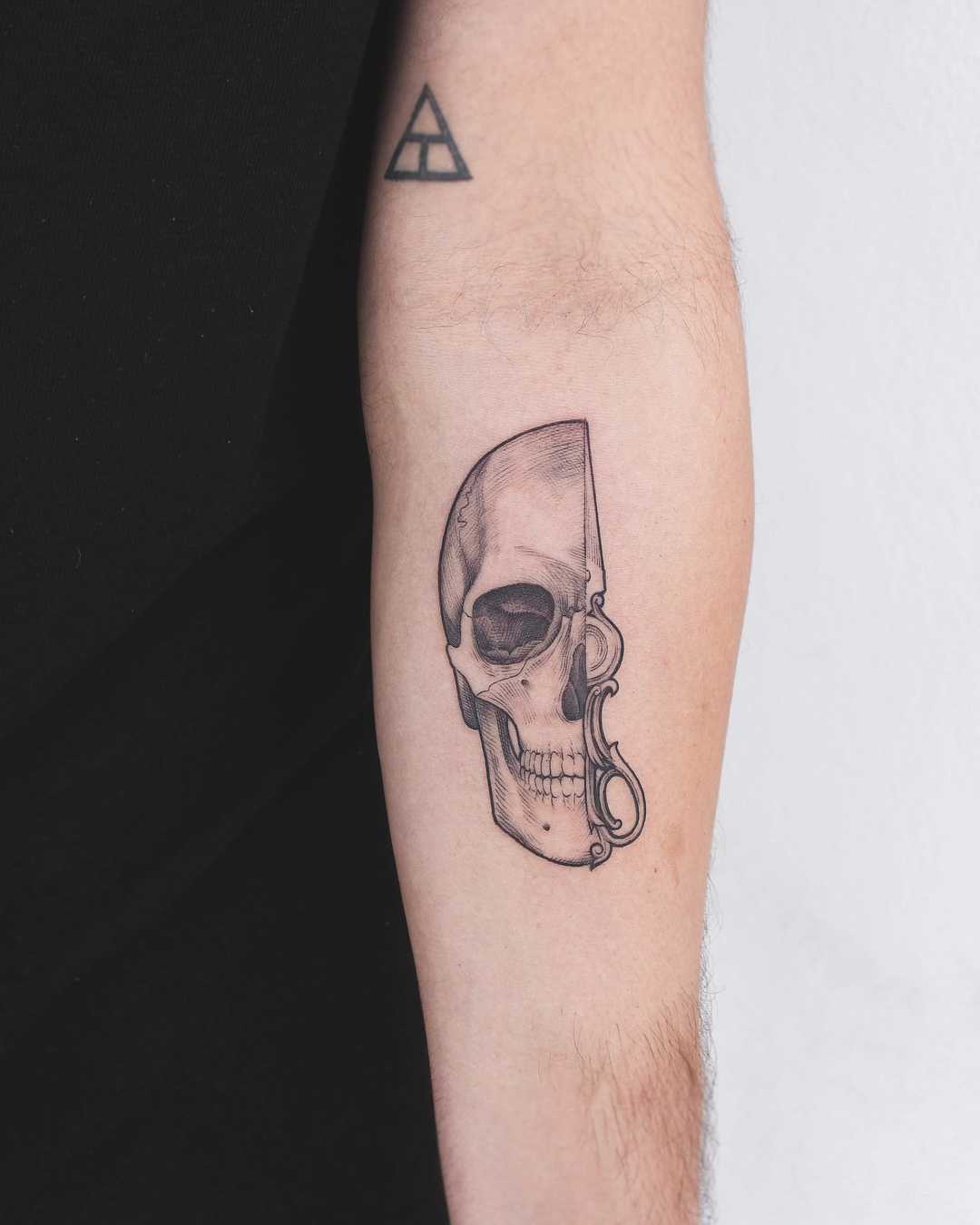 Half skull tattoo on the left forearm