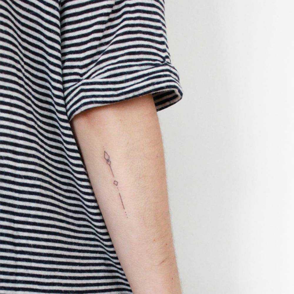 Hand-poked small arrow tattoo on the forearm
