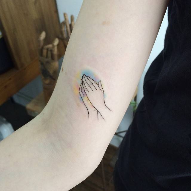 Small praying hands tattoo on the arm