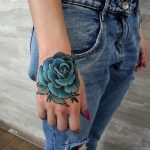 Teal rose tattoo on the hand