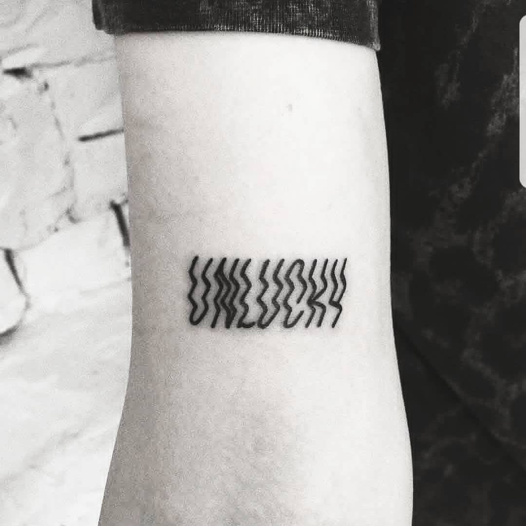Word unlucky tattoo by Ink And Water Tattoo