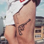 Black and white revolver tattoo on the thigh