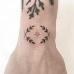 Hand-poked crossed twigs tattoo
