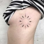 Hand-poked sun tattoo on the rib