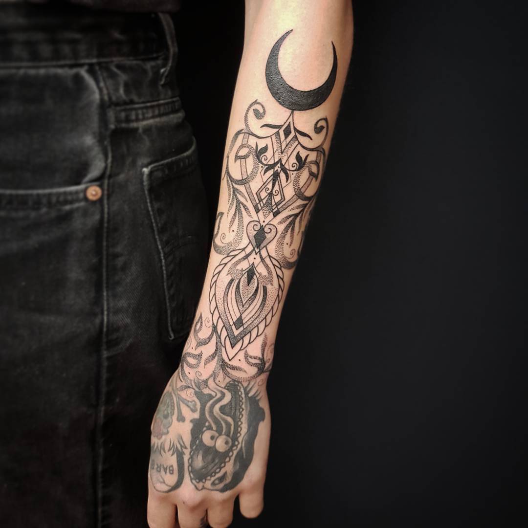 Ornaments and crescent moon tattoo on the forearm