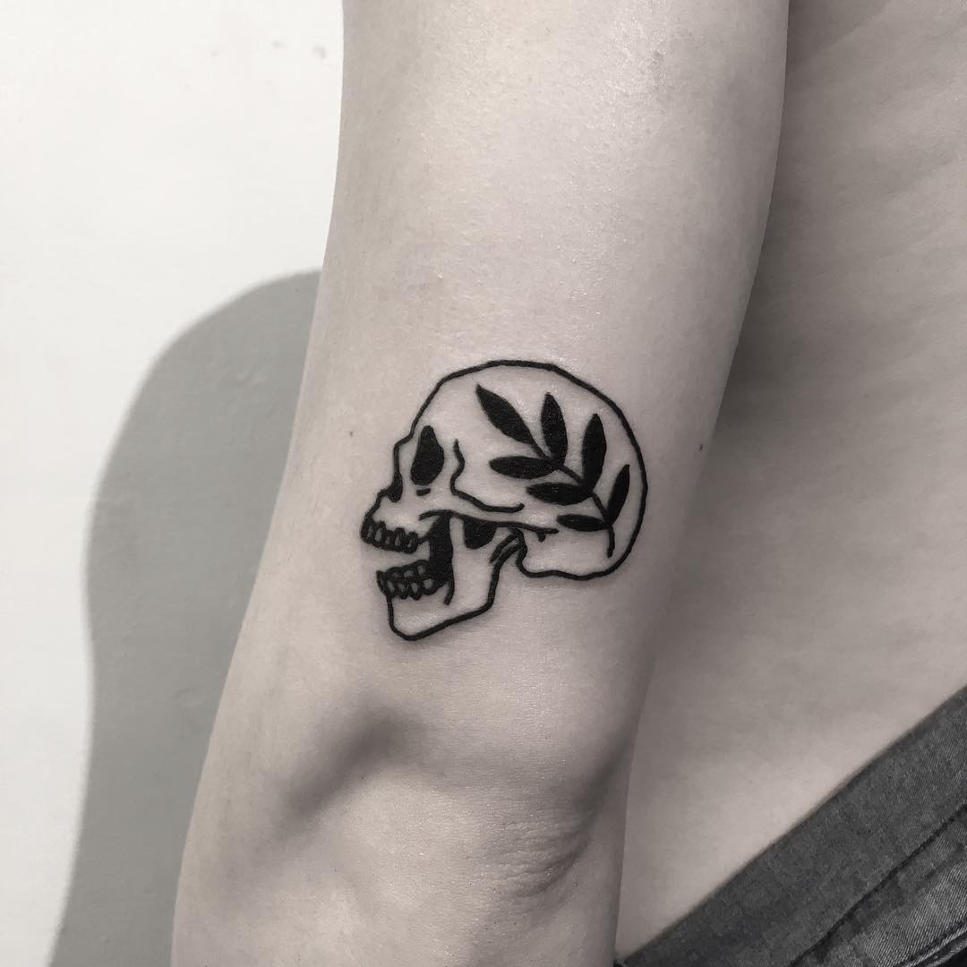 Small skull and branch tattoo