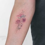 Tattoo of a lily, forget-me-nots, dahlia, peony, and fuchsia