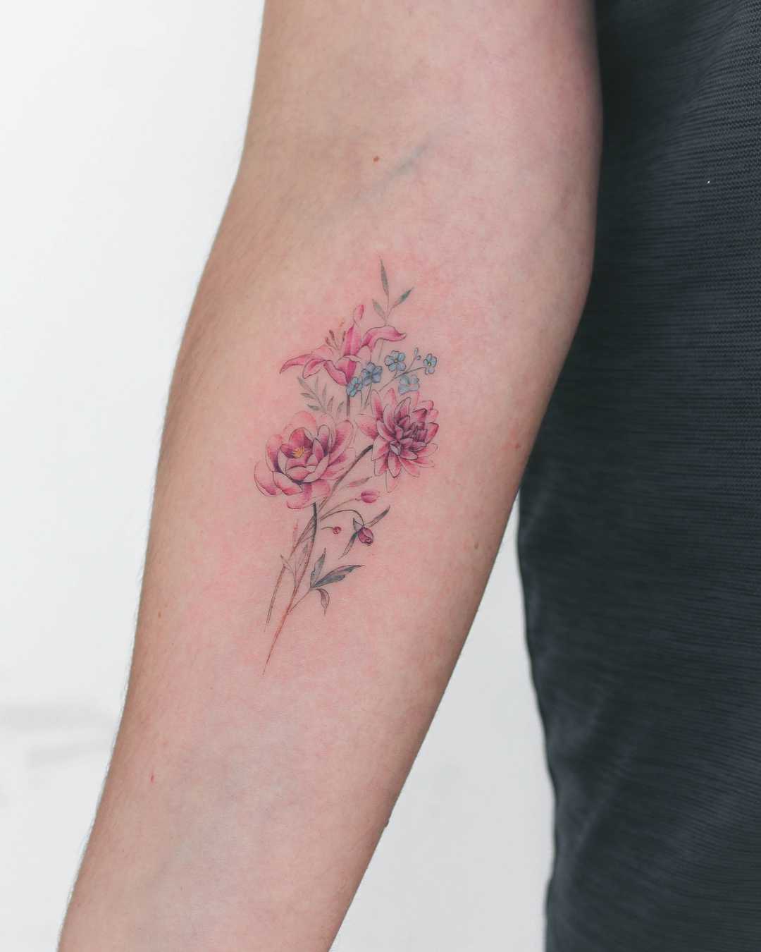 Tattoo of a lily, forget-me-nots, dahlia, peony, and fuchsia