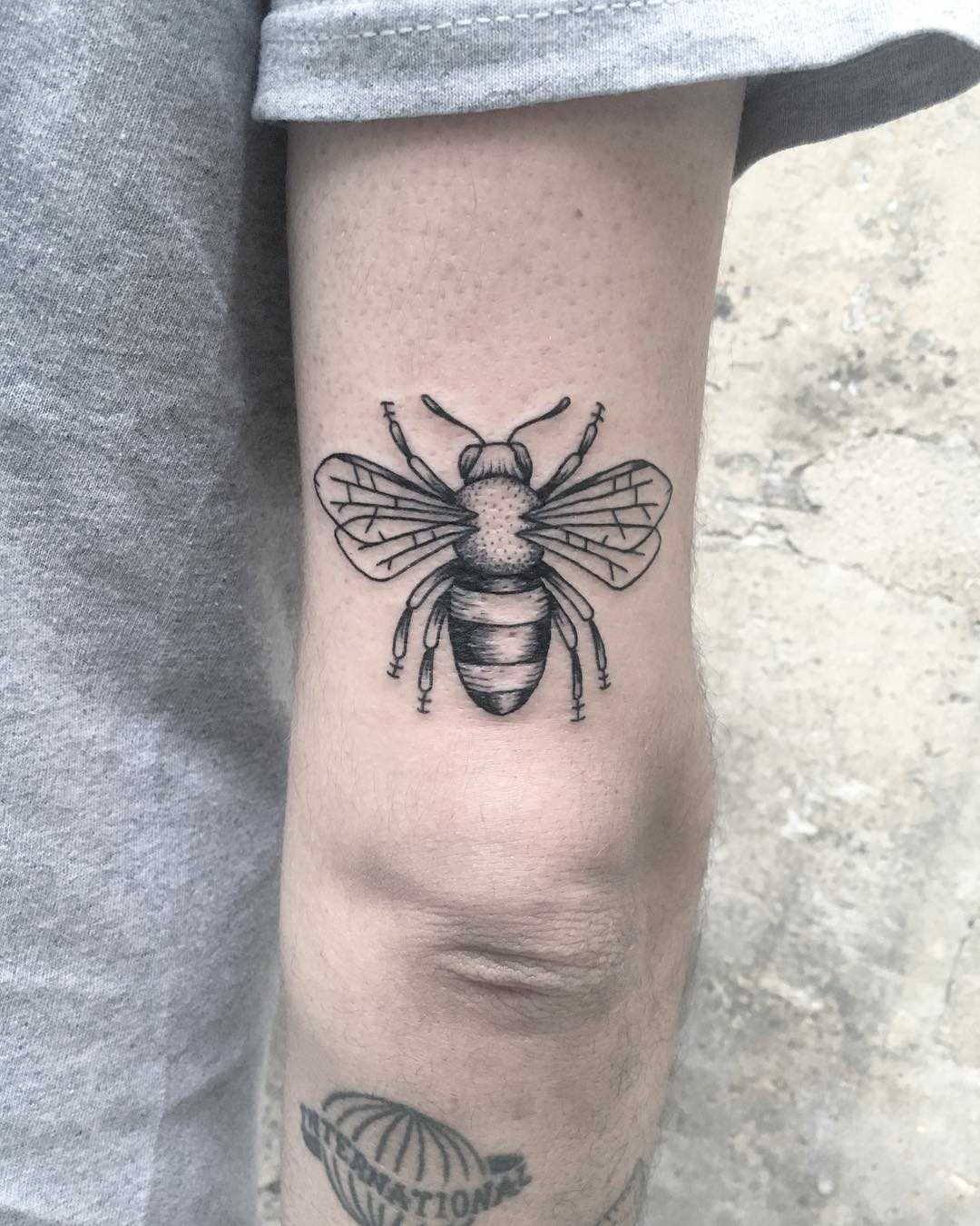 Black and grey bee tattoo on the triceps