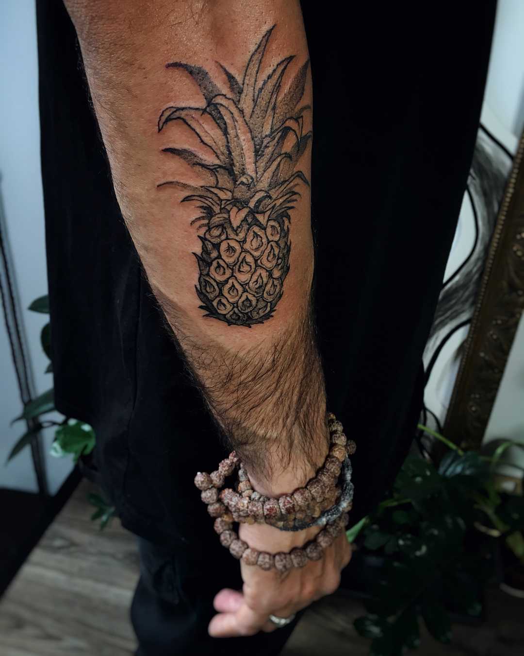 Black pineapple tattoo on the forearm
