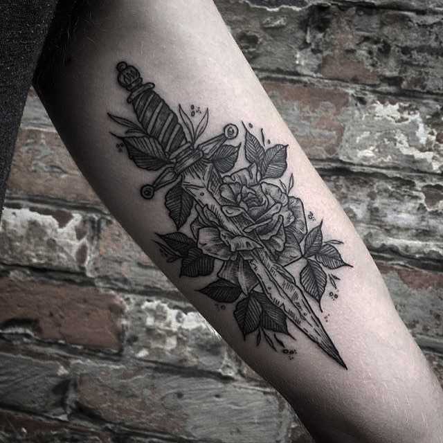 Blackwork rose and dagger tattooed on the arm