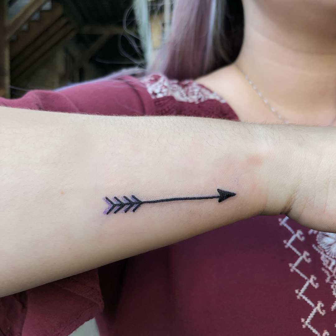 Minimalist arrow tattoo on the inner wrist.