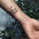 Tiny chevron pattern tattoo on the forearm