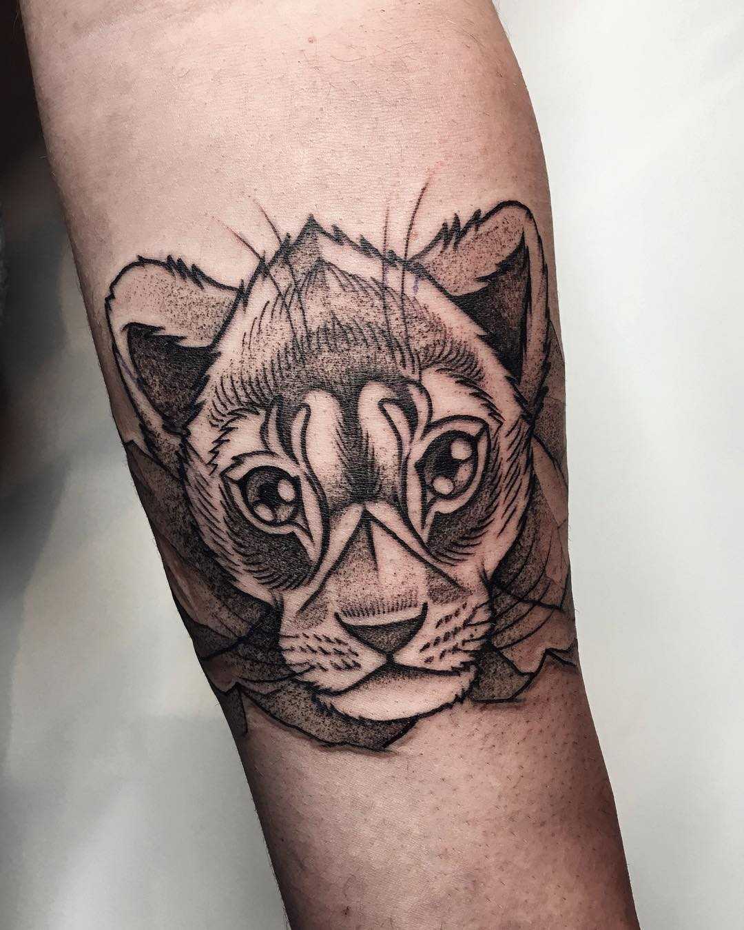 Young curious lion tattoo