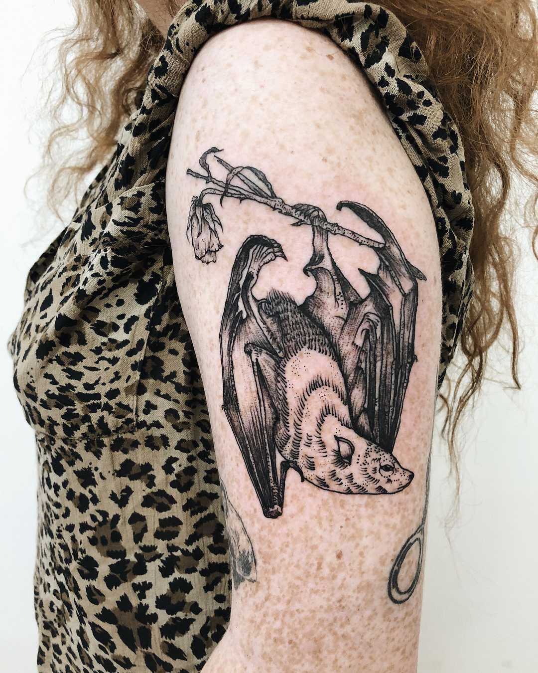 Bat hanging on to a dead rose tattoo
