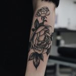 Black and grey peony tattoo on the forearm